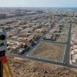 جهاز مسح هندسي أمام أحياء سكنية ترمز للسجل العقاري في مكة وجدة