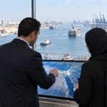 مختصان يراجعان خريطة تجارة رقمية داخل مركز لوجستي مطل على ميناء